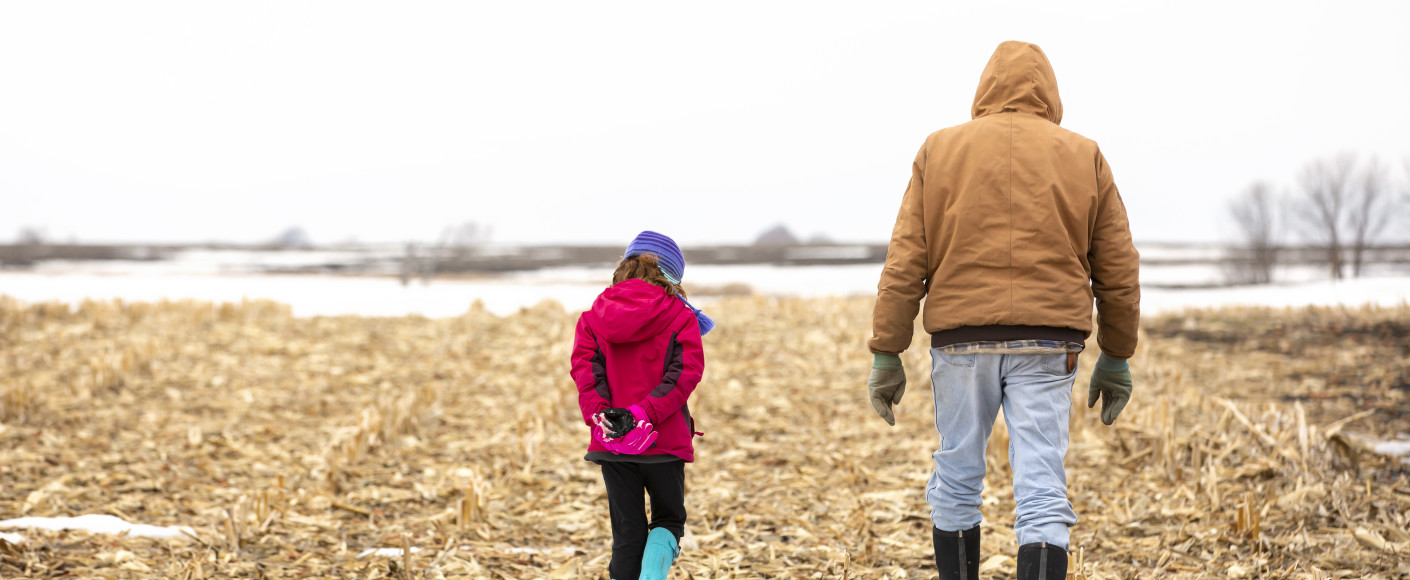 Granddaughter and grandfather in a winter corn field